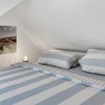 Bedroom with sloped ceiling, bed with striped cover, and wall art.