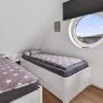 Two beds with star-patterned bedding and round porthole window in an attic room.