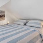 Bedroom with double bed, striped bedding, and wall art on sloped ceiling.