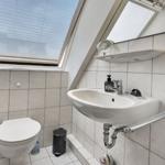 Bathroom with sink, toilet, and skylight. Tiled walls and floor.