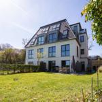 Modern villa with large garden and terrace. Multiple windows and skylights visible.