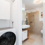 Washing machine next to bathroom with shower and sink
