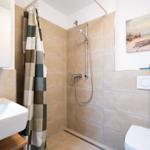 Bathroom with shower, sink, and toilet. Wall picture and shower curtain visible.