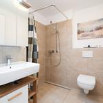 Bathroom with shower, sink, and toilet. Wall art and shower curtain are visible.