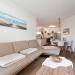 Living area with sofa, coffee table, and kitchen area in the background.