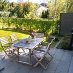 Terrace with table, four chairs, grill, and green lawn.