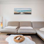 A living room with a light sofa, a wooden table, and a wall painting.