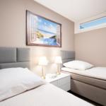 Two beds with headboards, nightstand, and wall picture with beach motif.