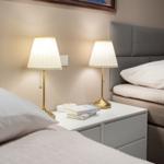 Two beds with headboards and nightstand with lamps and books.