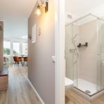 Hallway with bathroom and view into dining area with table and chairs.