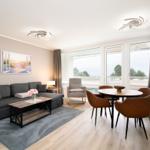 Living and dining area with sofa, table and chairs. Large windows with view of the outdoor area.