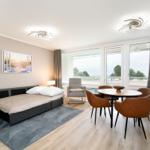 Sleeping area with sofa bed, dining table, and kitchen area with view.