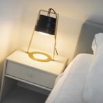 Schlafzimmer mit Nachttisch und Lampe. Bett mit weißer Bettwäsche.