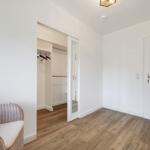 Zimmer mit Kleiderschrank, Holzboden und Wicker-Sofa mit Kissen.