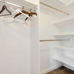 Kleiderständer mit Haken und Regale mit Handtüchern im Schrank.