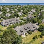 Dorf mit strohgedeckten Häusern und grünen Gärten am Meer