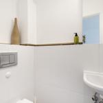 Bathroom with sink, mirror, and toilet. Walls covered with white tiles.
