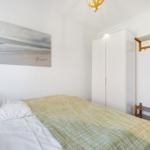 Bedroom with bed, coat rack, and wall picture on the wall.