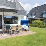 Terrace with table, chairs, and umbrella. Lawn and beach chair in background.