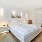 Bedroom with white bed, nightstand, and wardrobe.
