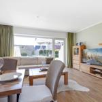 Living and dining area with wooden furniture, TV, and view of the garden.