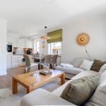 Living area with sofa, table, and kitchen area in the background.