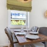 Dining room with table, chairs, and window view. Wall decor and ceiling light.