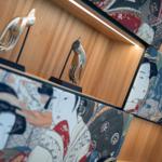 Wand mit japanischen Kunstwerken und Metallskulpturen von Händen.