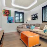 Wohnzimmer mit Sofa, orangefarbenem Couchtisch und Wandbildern.