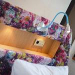 Bettkopfteil mit buntem Stoff und Steckdose