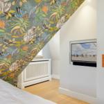Schlafzimmer mit Tiermotiv-Wandtapete, Fernseher und weißem Heizkörper.