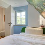 Schlafzimmer mit Bett, Fenster und Badezimmer. Decke mit Tiermotiven.