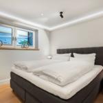 Schlafzimmer mit Bett, Nachttisch und Fenster mit Meerblick.