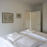 Zwei Betten mit weißen Bettwäsche und Handtüchern. Wand mit drei Bildern und Kleiderschrank.
