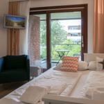 Schlafzimmer mit Balkon, Bett, Sessel und Fernseher.