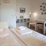 Zwei Betten mit weißen Laken und Handtüchern. Tisch mit Stühlen und Wandbilder.