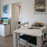 Essbereich mit weißem Tisch und Stühlen. Fernseher und Bilder an der Wand.