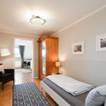 Bedroom with bed, wardrobe, and seating. Passage to living area.