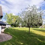 House with terrace, flowering tree, and playground in the garden.