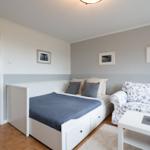 Bedroom with bed, sofa, and table. Walls painted in two colors.