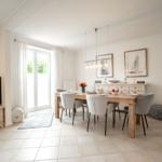 Dining room with wooden table, chairs, and window. TV on sideboard.