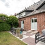 Red brick house with terrace, garden, and seating areas.