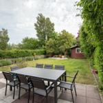 Terrace with table and chairs, lawn area, and small red garden shed.