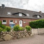 Red brick house with dormers and a well-kept garden with stone wall and wooden fence.