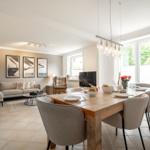 Dining room with wooden table and chairs. Living room with sofa and wall art.