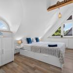 Schlafzimmer mit Dachschräge, Bett, Schrank und Fenster