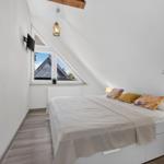Schlafzimmer mit Dachschrägen, Bett, Fenster und Wand-TV.