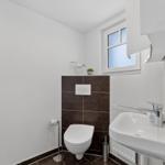 Badezimmer mit Toilette, Waschbecken und Fenster