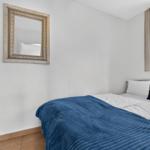 Schlafzimmer mit Bett, Spiegel und Fenster.