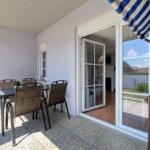 Terrasse mit Tisch, Stühlen und Schiebetür zum Innenraum.